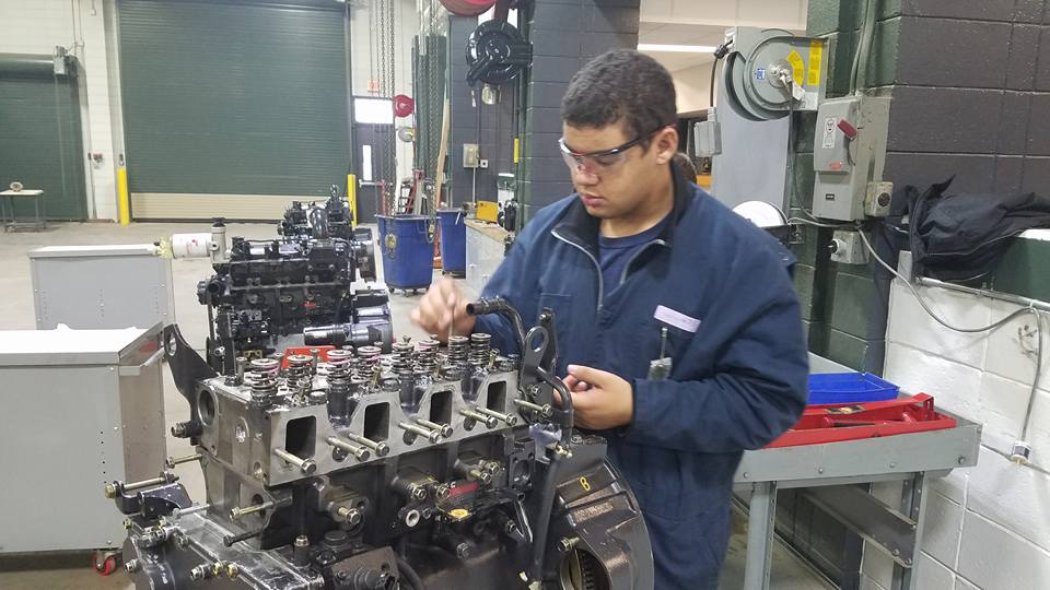 Picture of student removing push rods from the engine he is working on during the disassembling process.